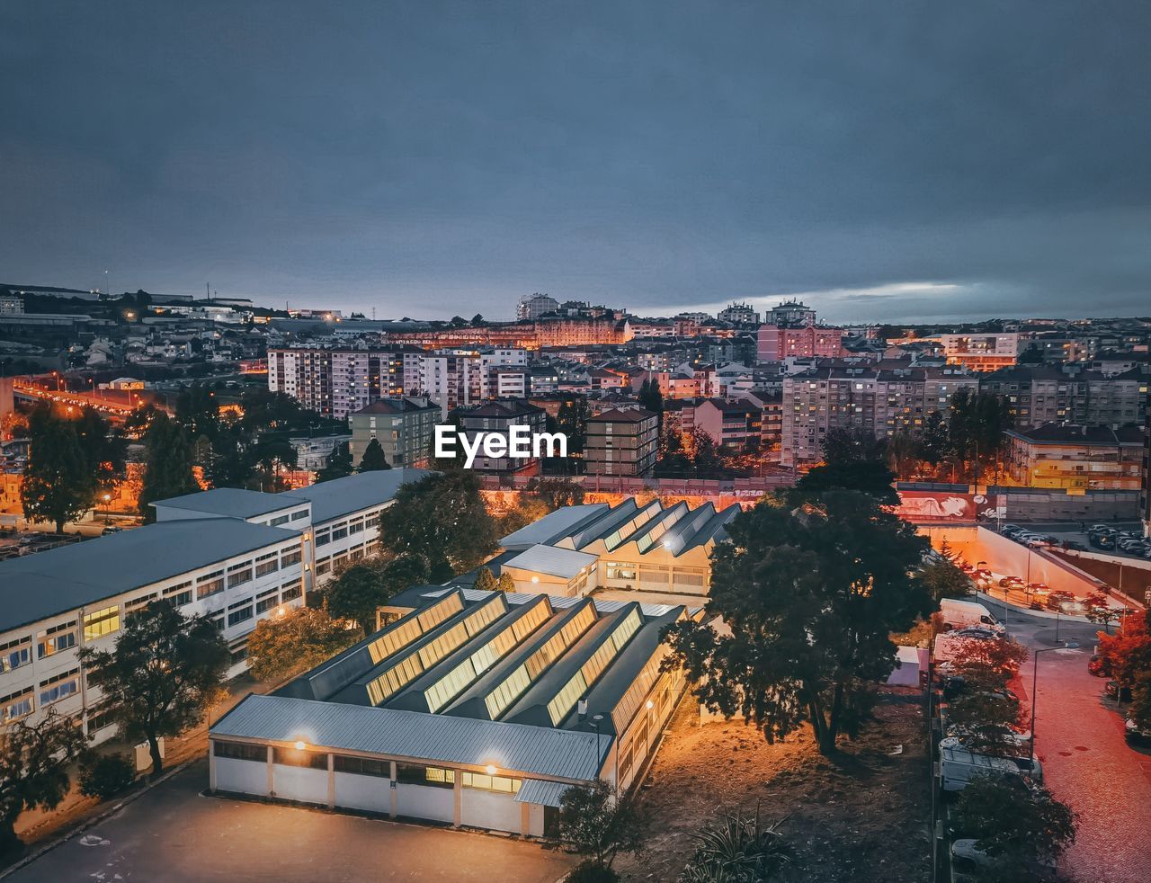 HIGH ANGLE VIEW OF ILLUMINATED CITY BUILDINGS AT DUSK