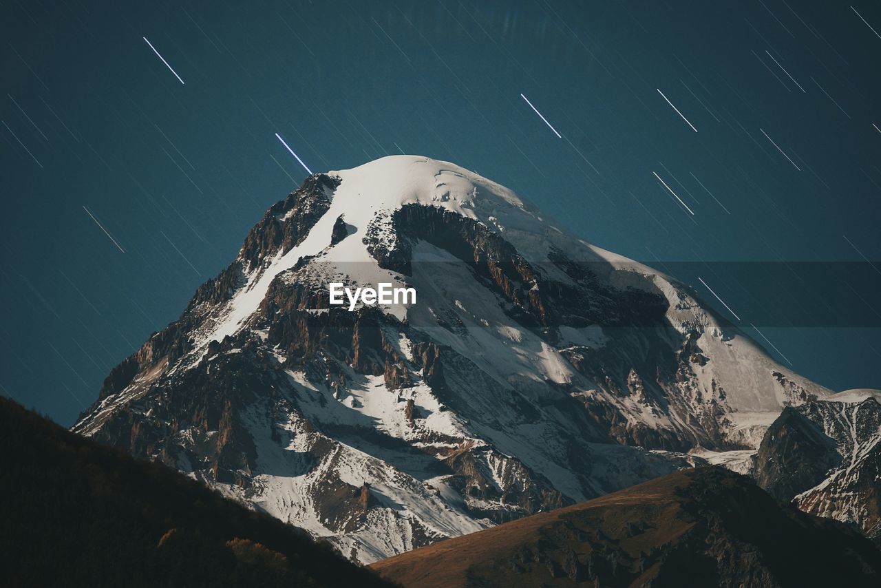 Scenic view of snow covered mountain against star field