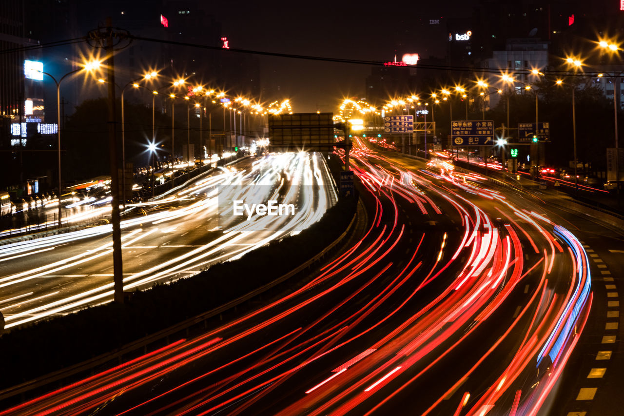 Light trails on city street against clear sky at night