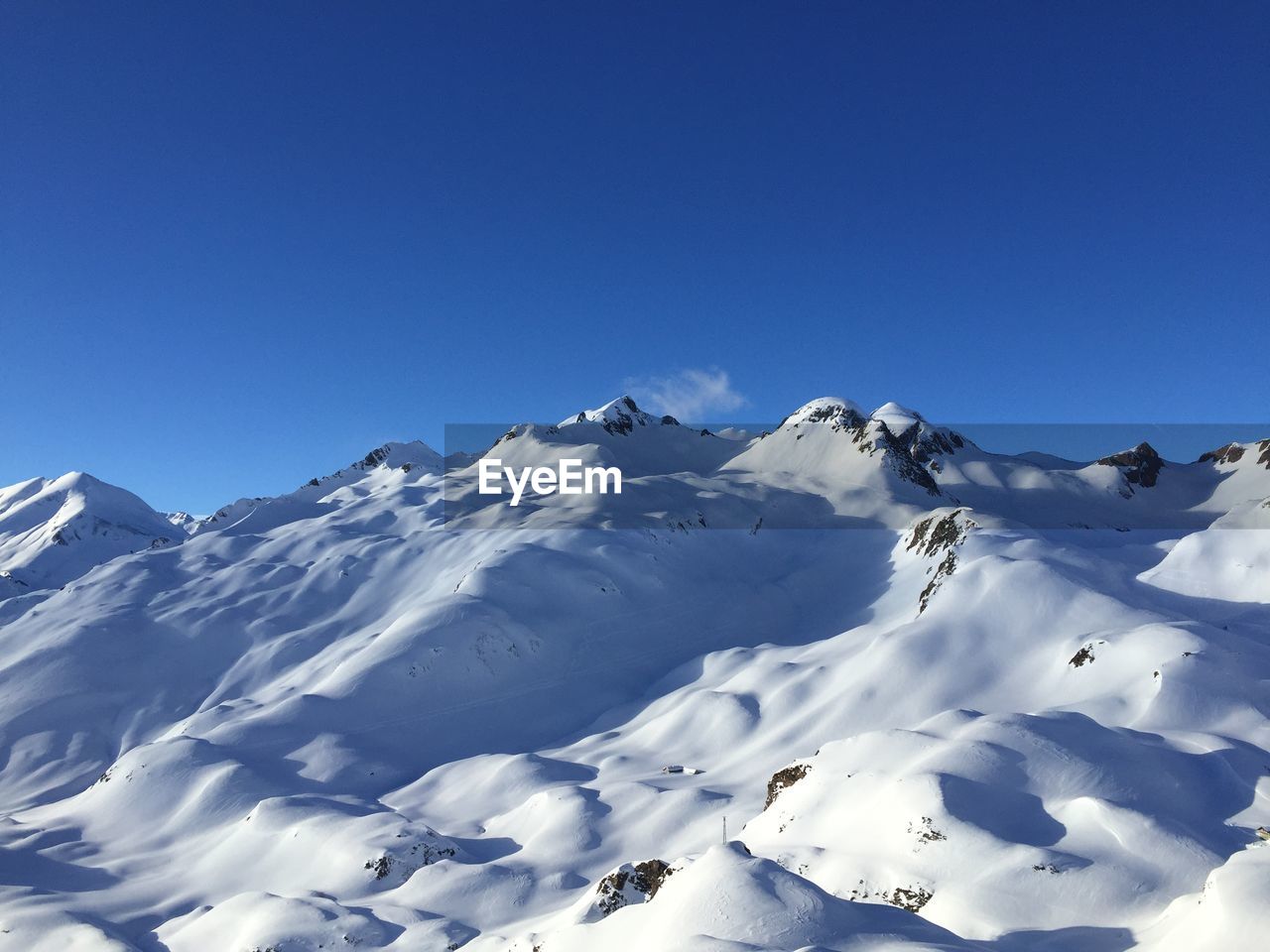 Scenic view of snowcapped mountains against clear blue sky