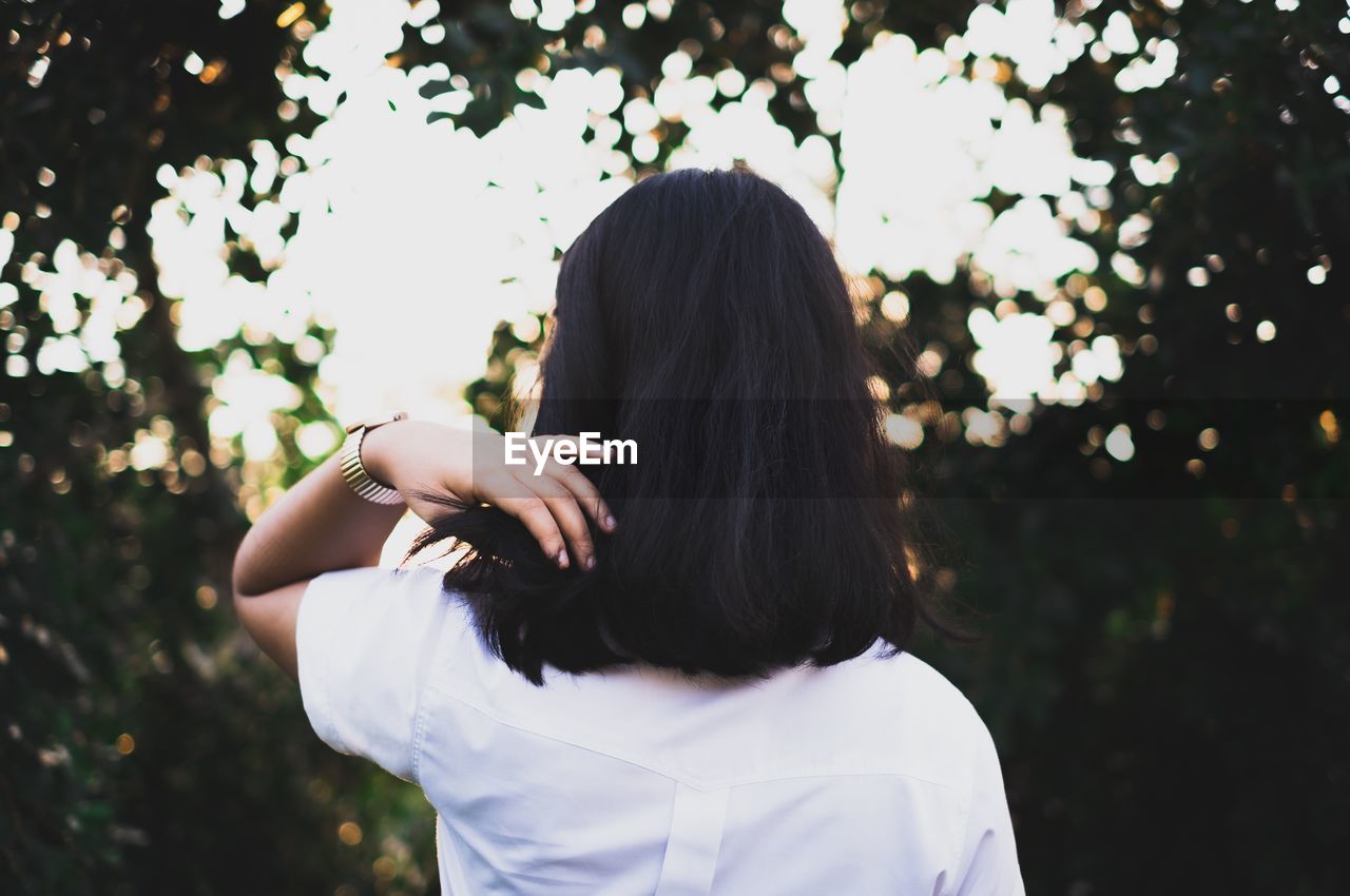 Rear view of woman standing against trees