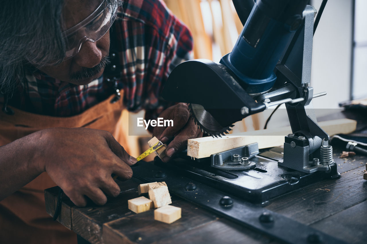 MIDSECTION OF MAN WORKING ON TABLE AT HOME