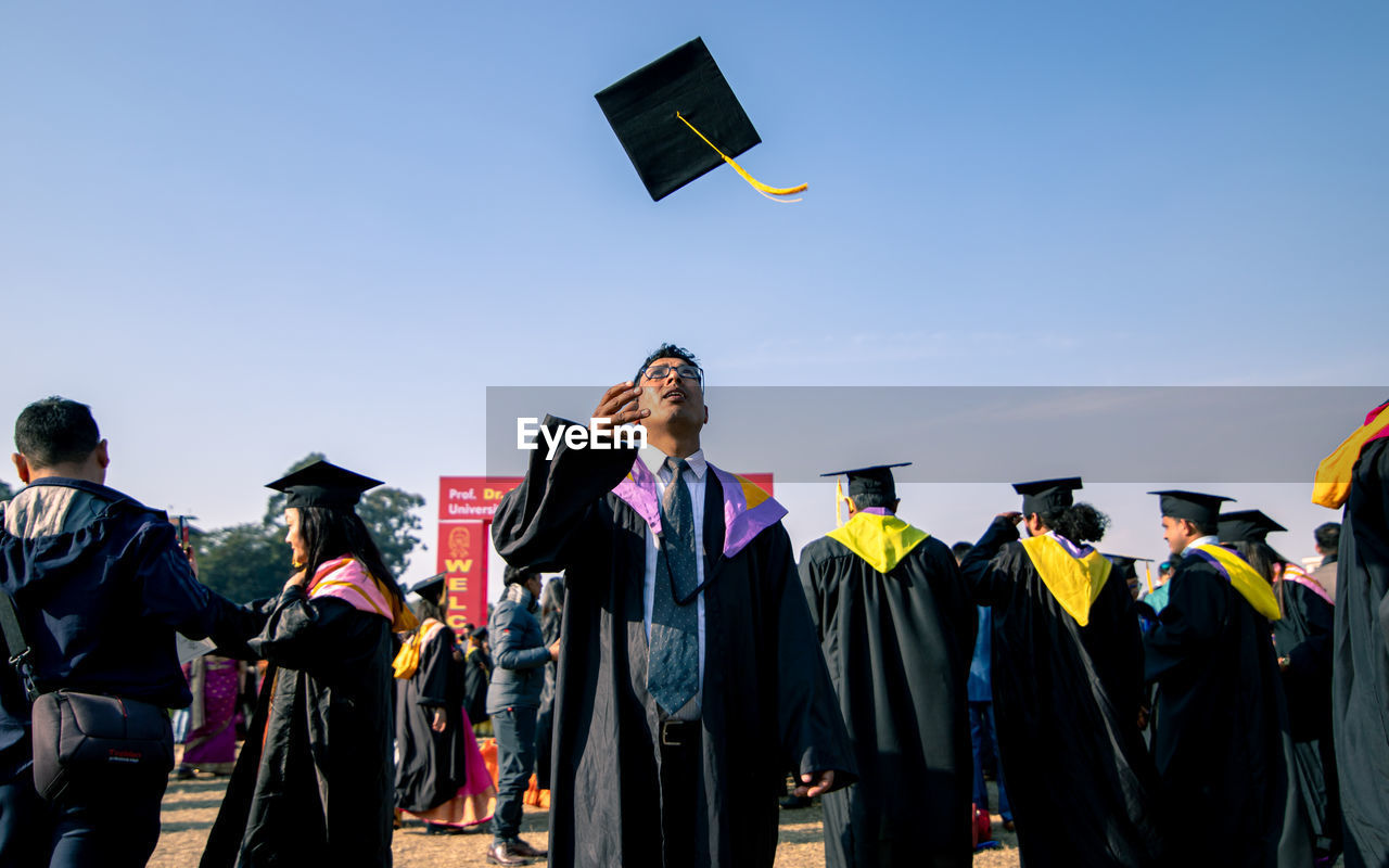 Man looking up while throwing mortarboard in sky