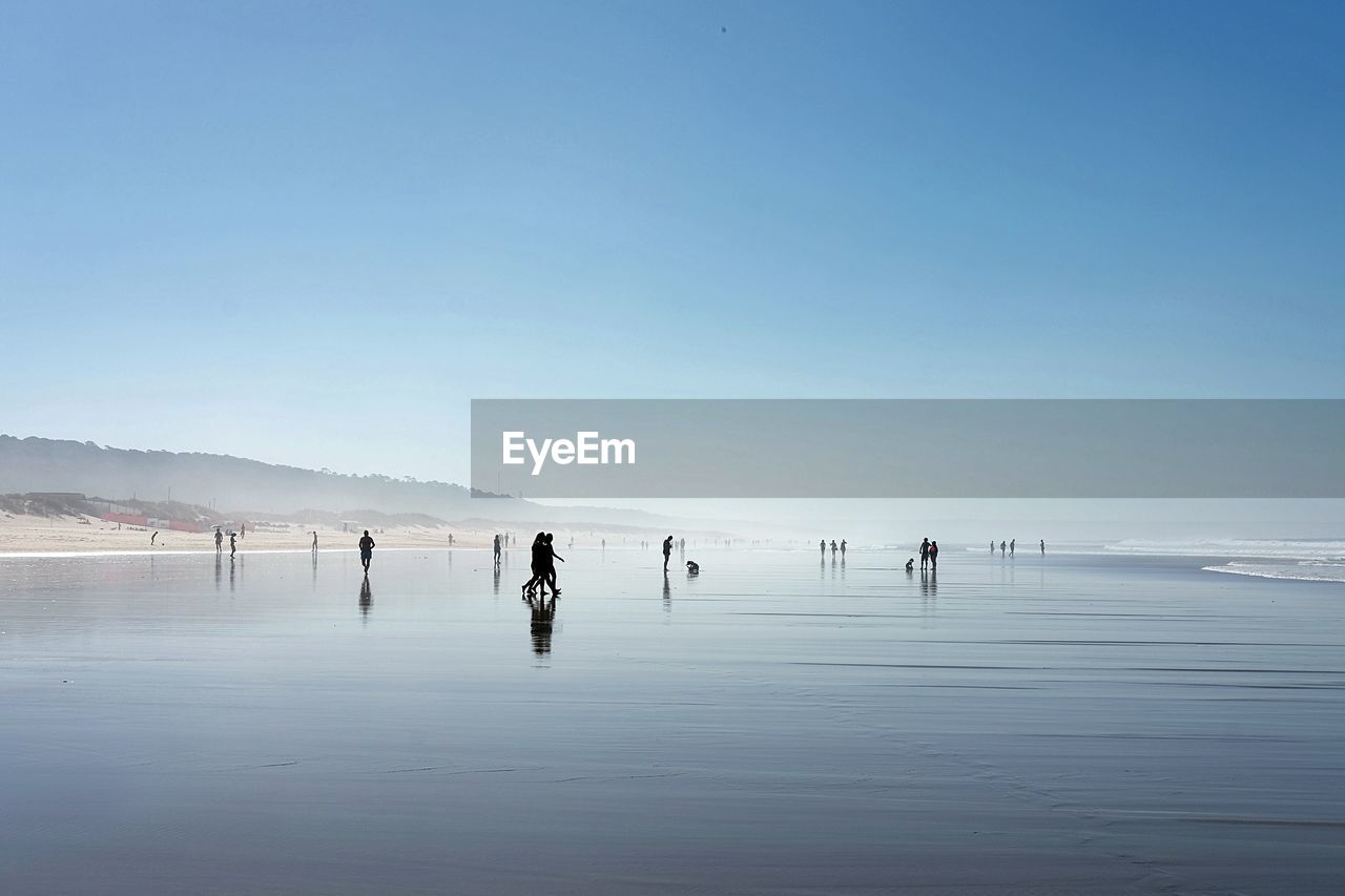 People at beach against sky