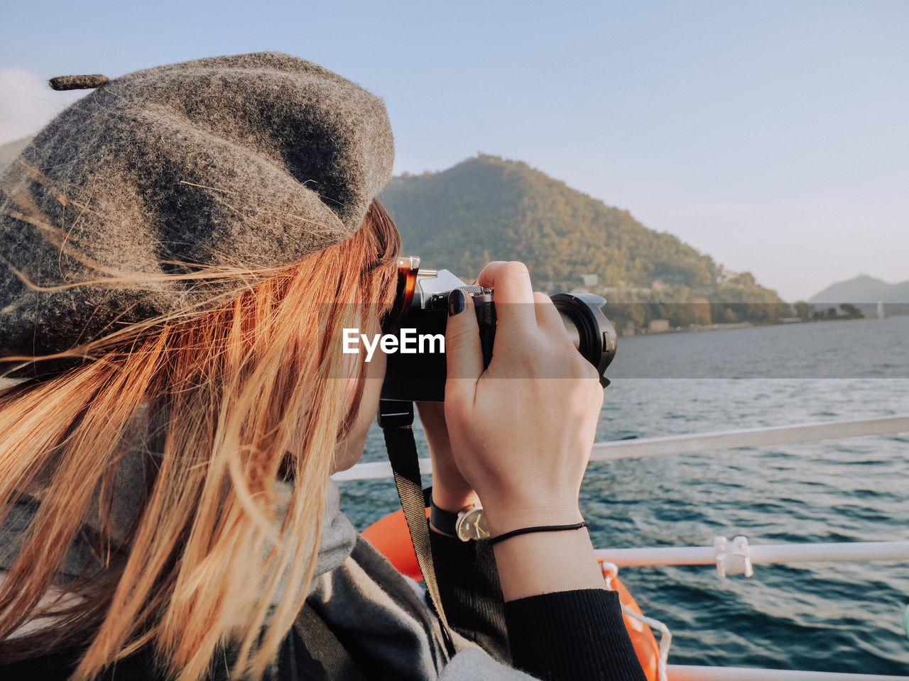 Close-up of woman photographing sea with digital camera against sky