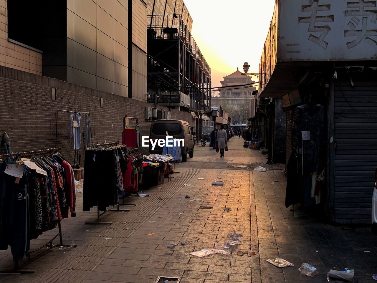 Clothes racks on messy footpath in city