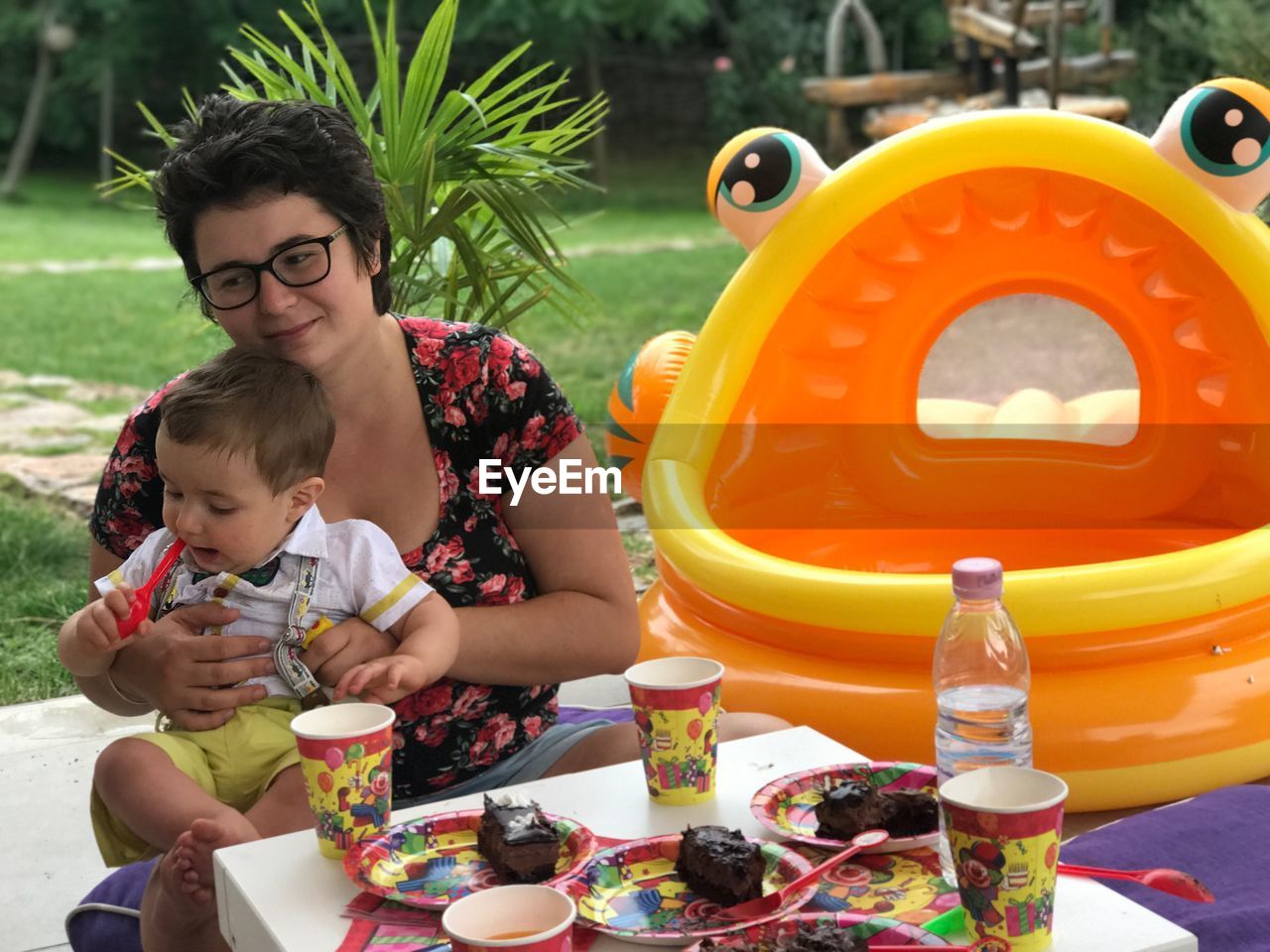 Mother with son having cakes by inflatable raft at yard