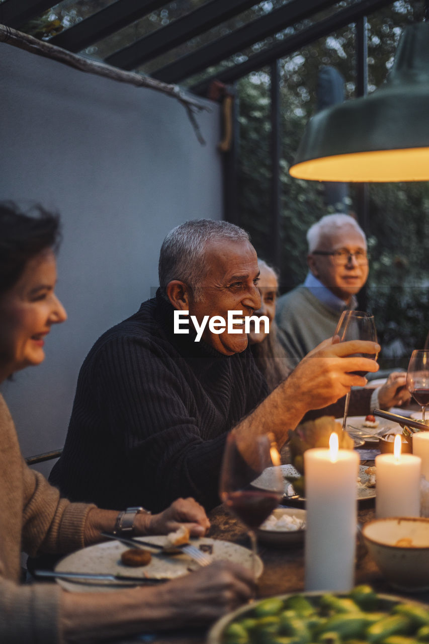 Happy mature man enjoying with retired friends during dinner party