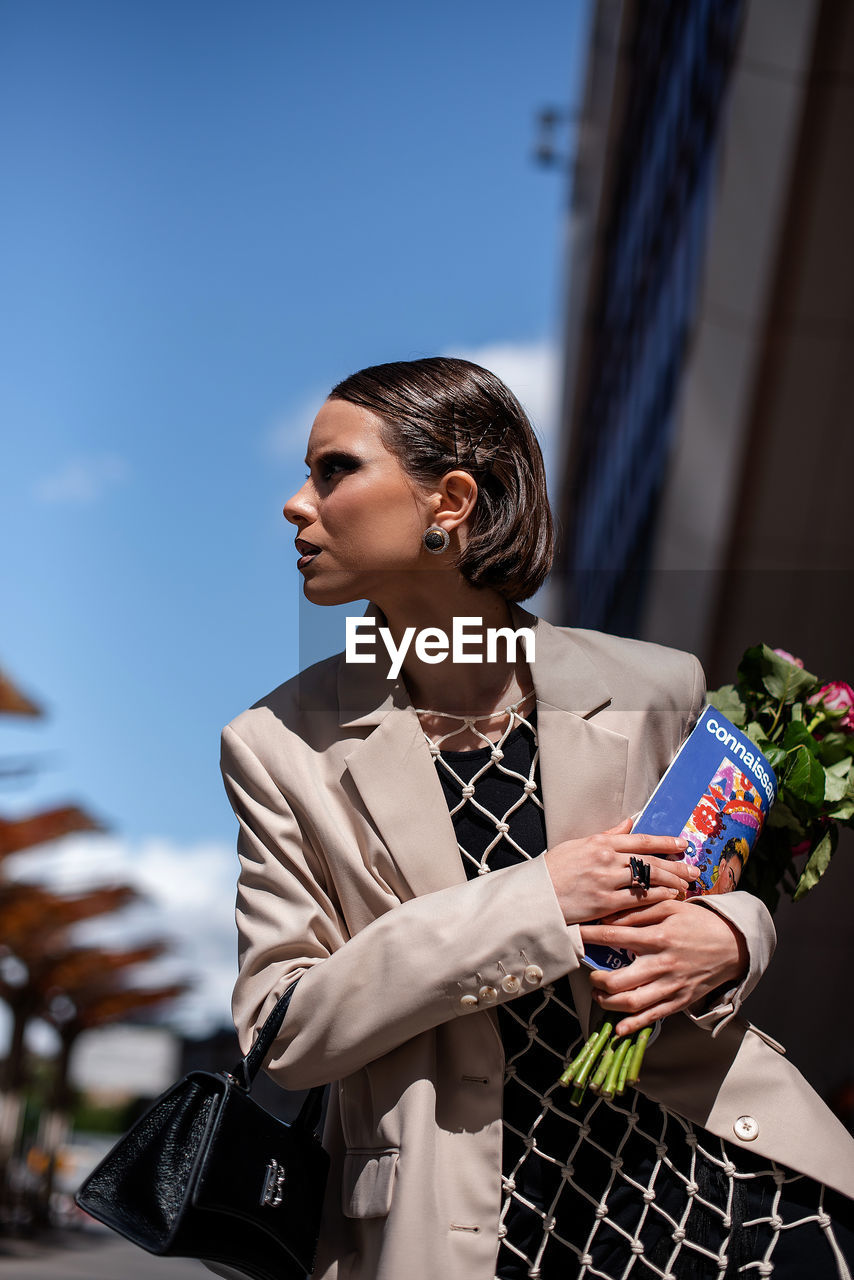 Side view of women using magazine and bouquet 