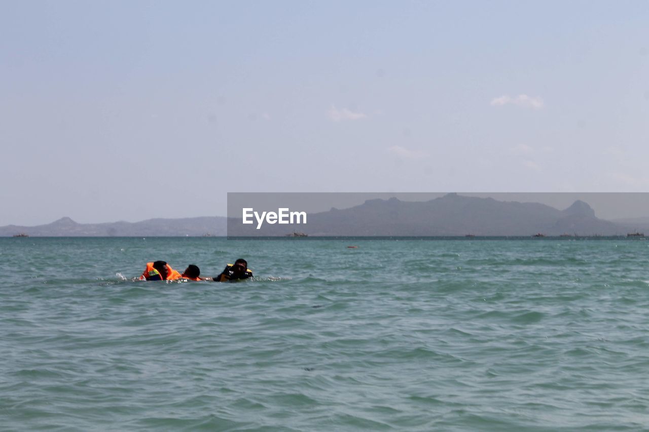 PEOPLE ON BOAT IN SEA AGAINST SKY