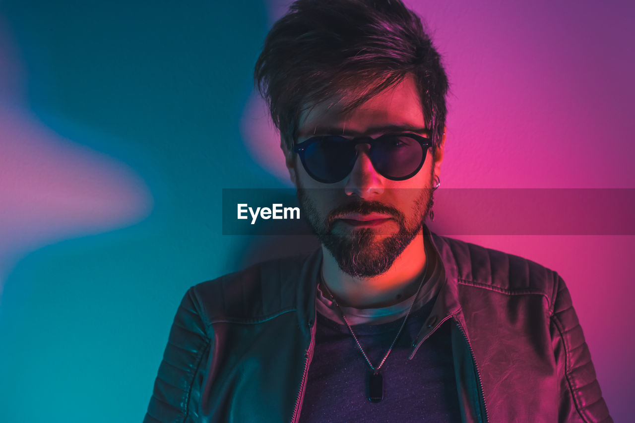 Portrait of young man wearing sunglasses against gray background