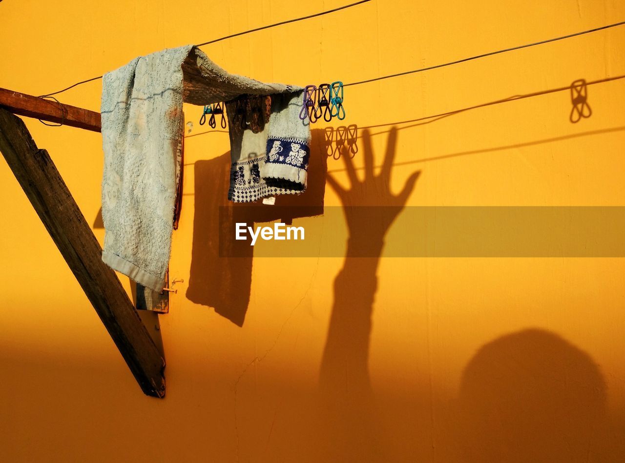 Low angle view of clothes line against yellow wall