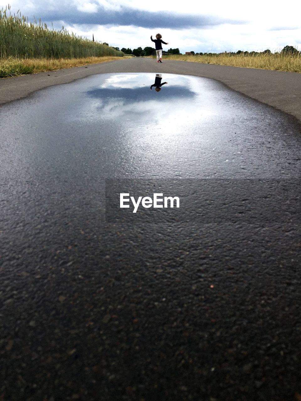 Rear view of boy reflection on country road