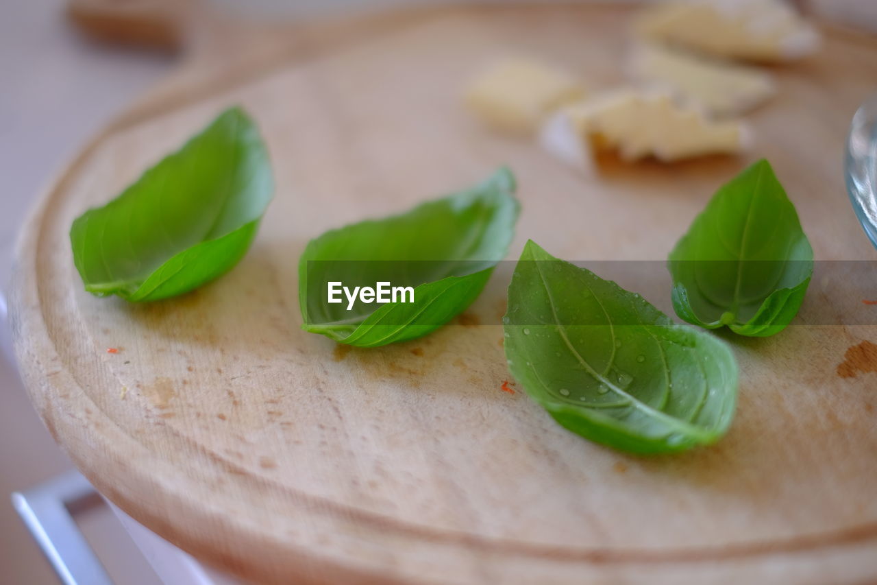 CLOSE-UP OF GREEN CHILI PEPPERS LEAVES ON TABLE