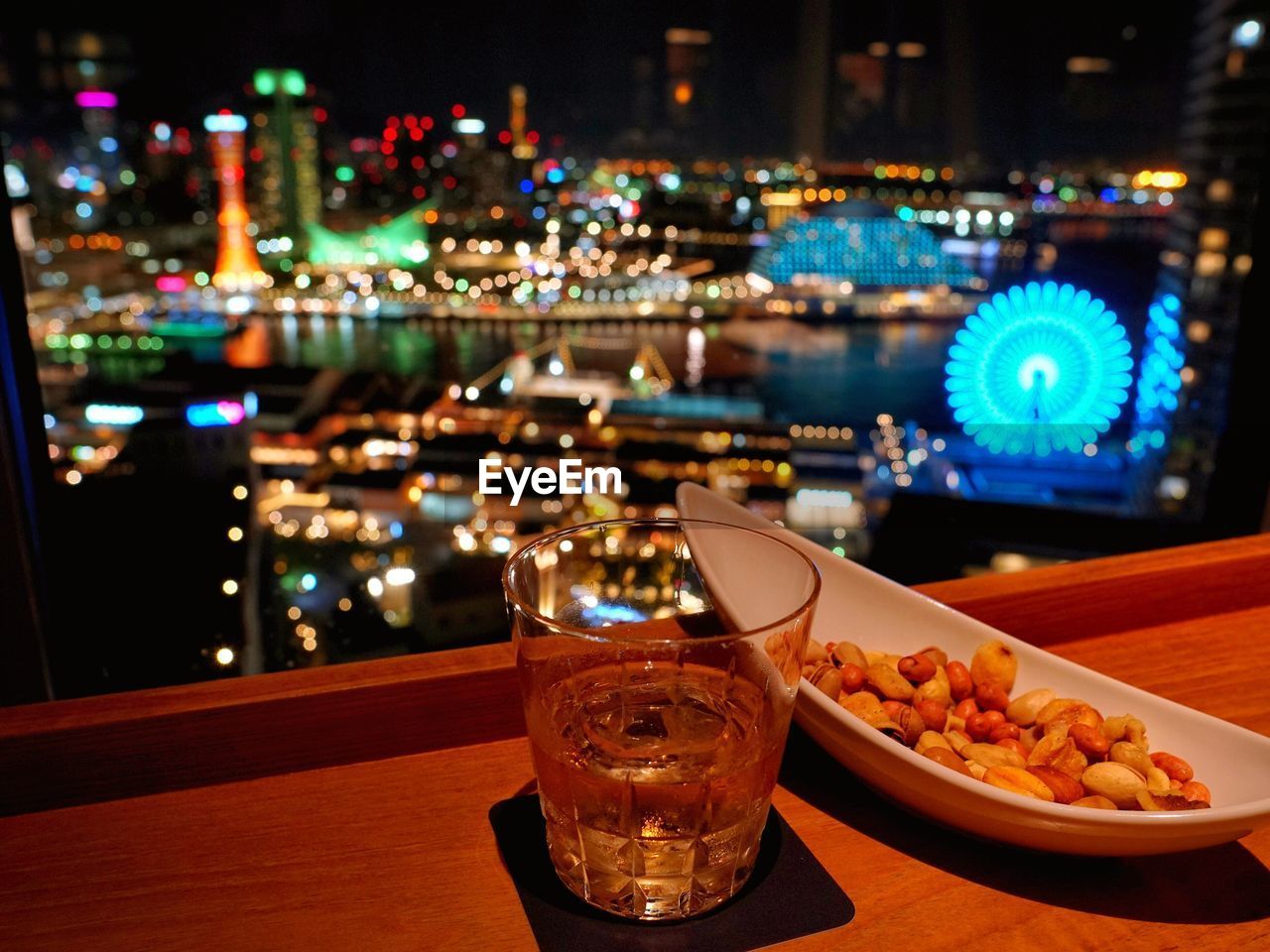 Close-up of food and drink on table with illuminated city in background at night