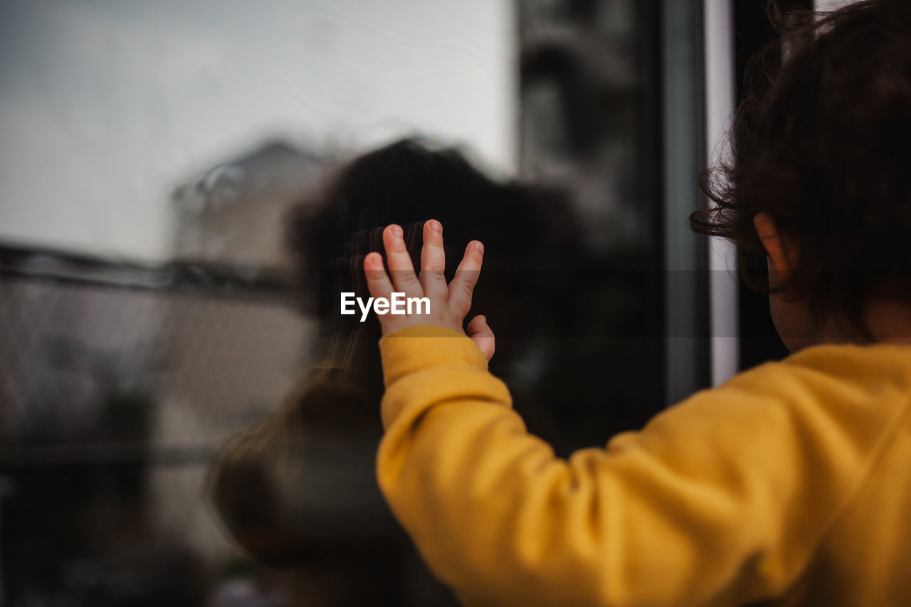 Rear view of child hand on window