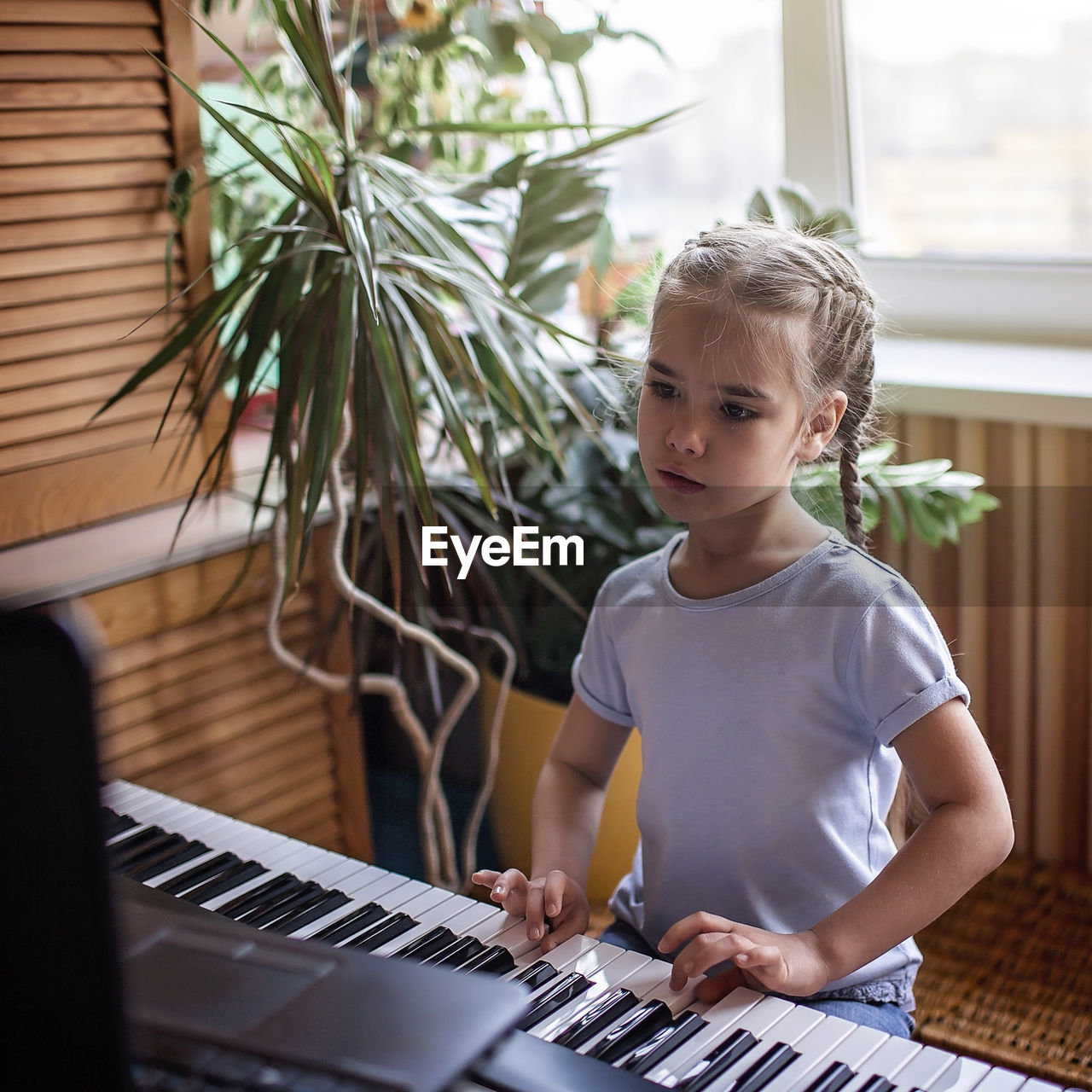 Young musician playing classic digital piano at home during online class at home, self-isolation