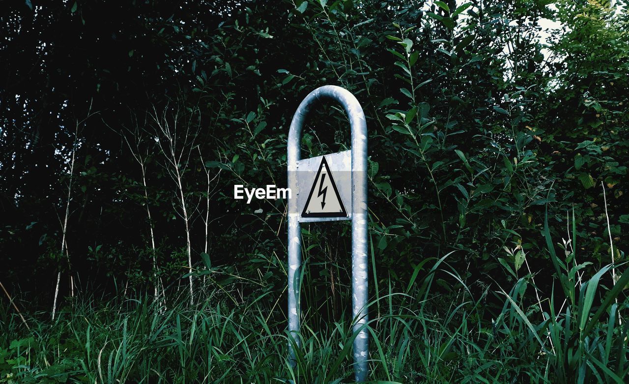 INFORMATION SIGN ON FIELD BY TREES