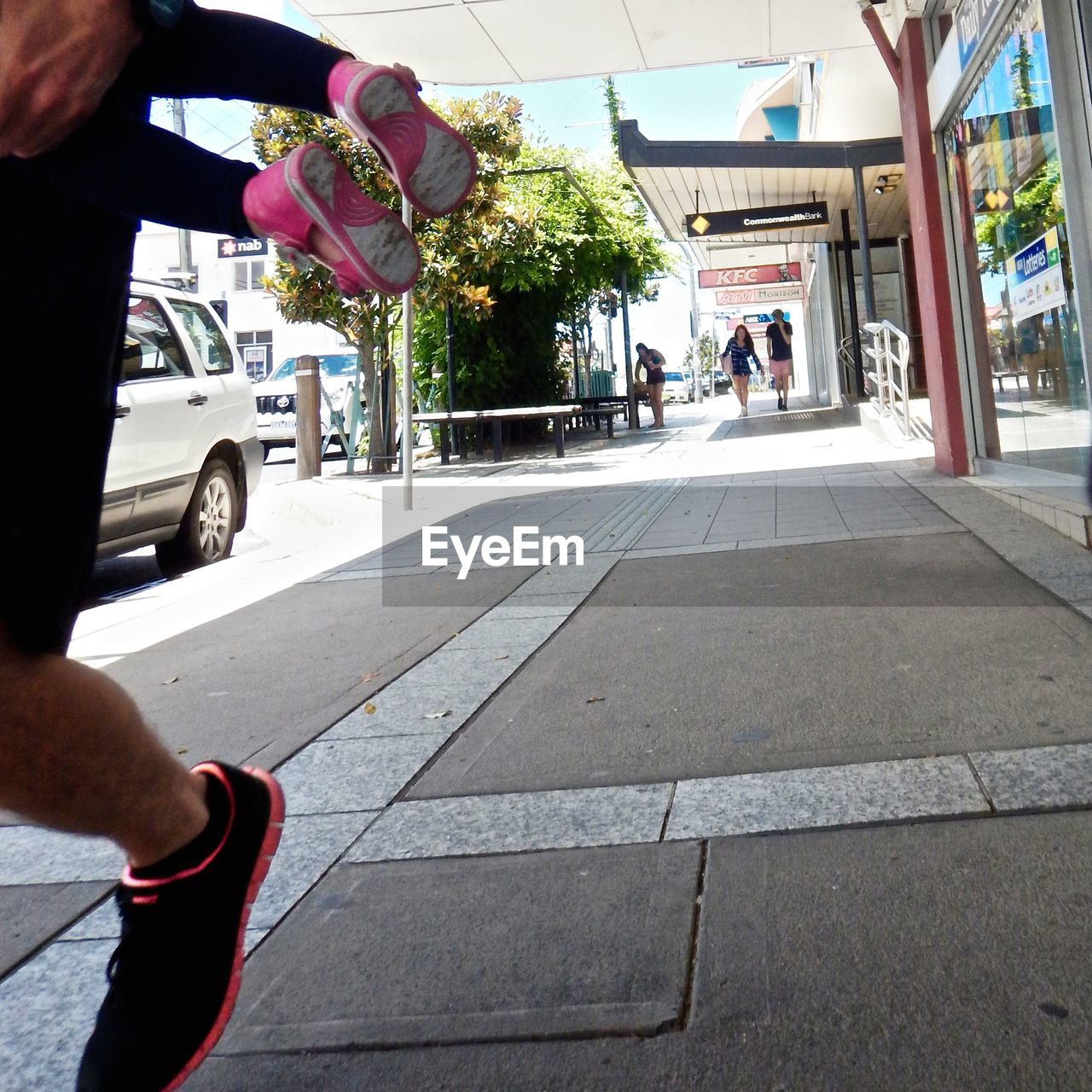 Cropped image of man holding child on sidewalk during sunny day