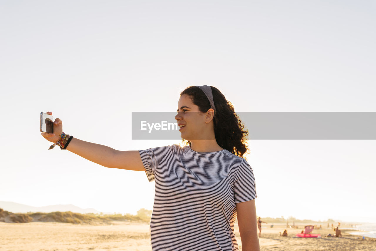 Man photographing on beach against clear sky