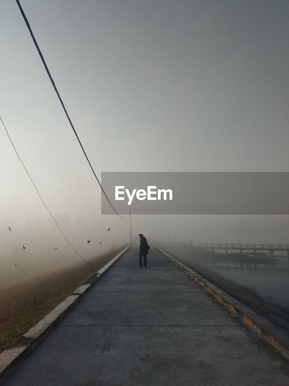 Rear view of person walking on road against sky