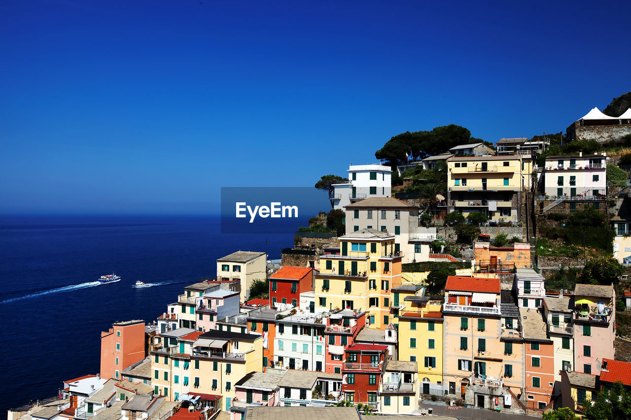 Townscape by ocean against clear blue sky