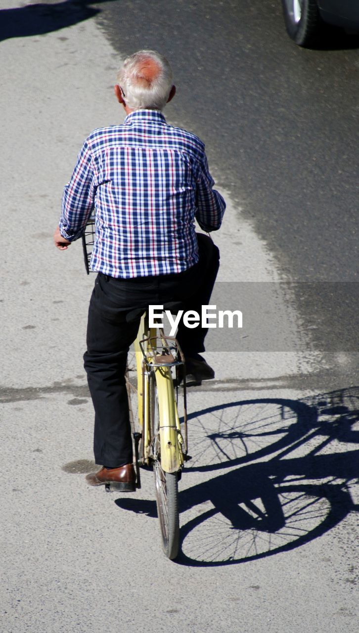 Rear view of man riding bicycle on street