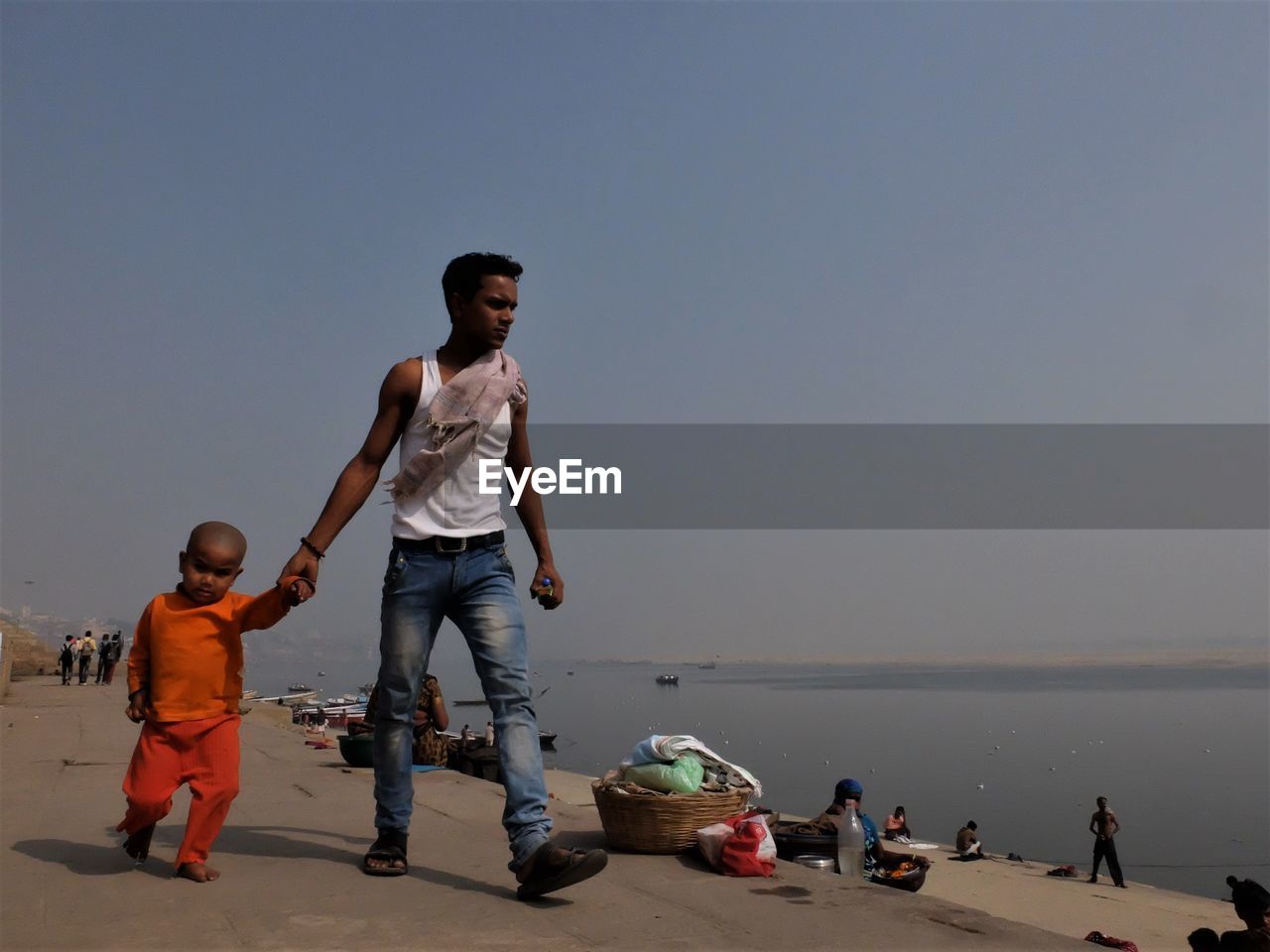 FULL LENGTH OF FATHER AND DAUGHTER WALKING ON BEACH