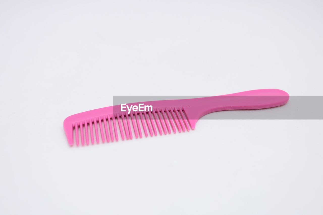 High angle view of pink comb on white background