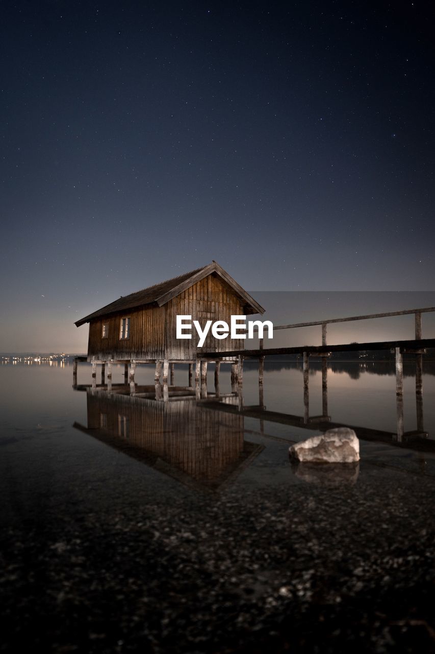 Scenic view shack by lake against sky at dusk