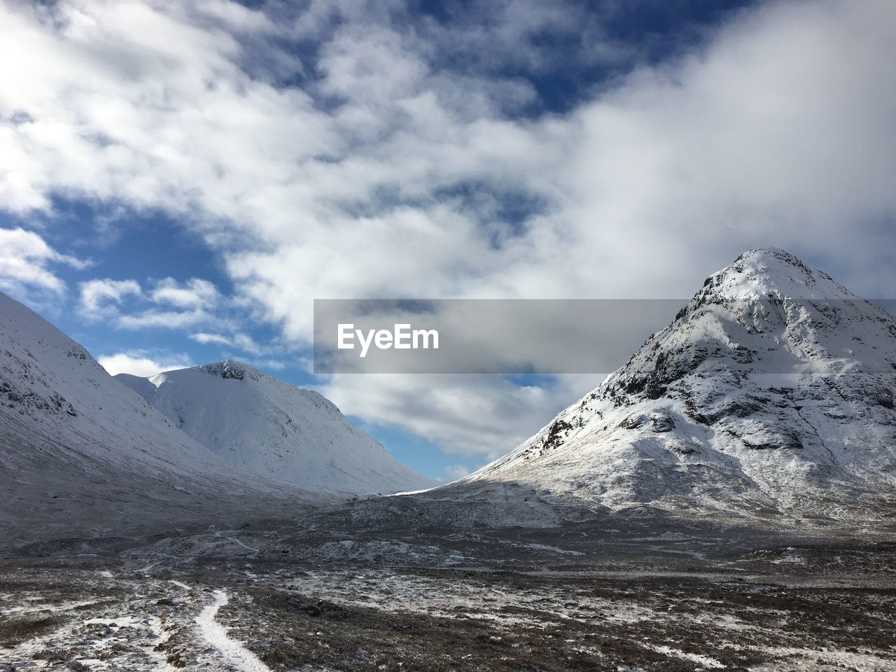 Scenic view of snow covered mountains against cloudy sky