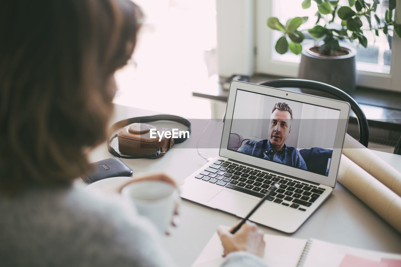 Woman having video conference call with male coworker