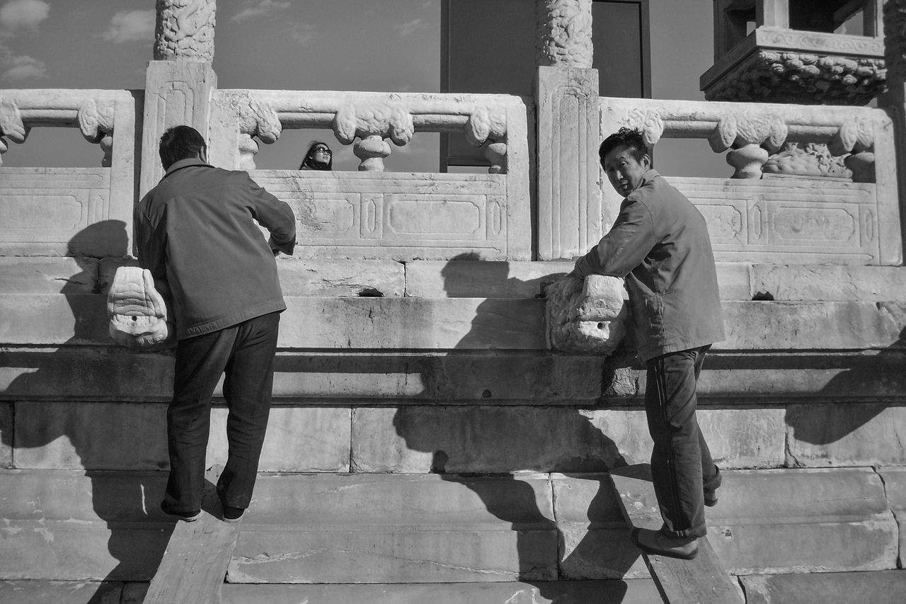 REAR VIEW OF PEOPLE WORKING ON BUILDING