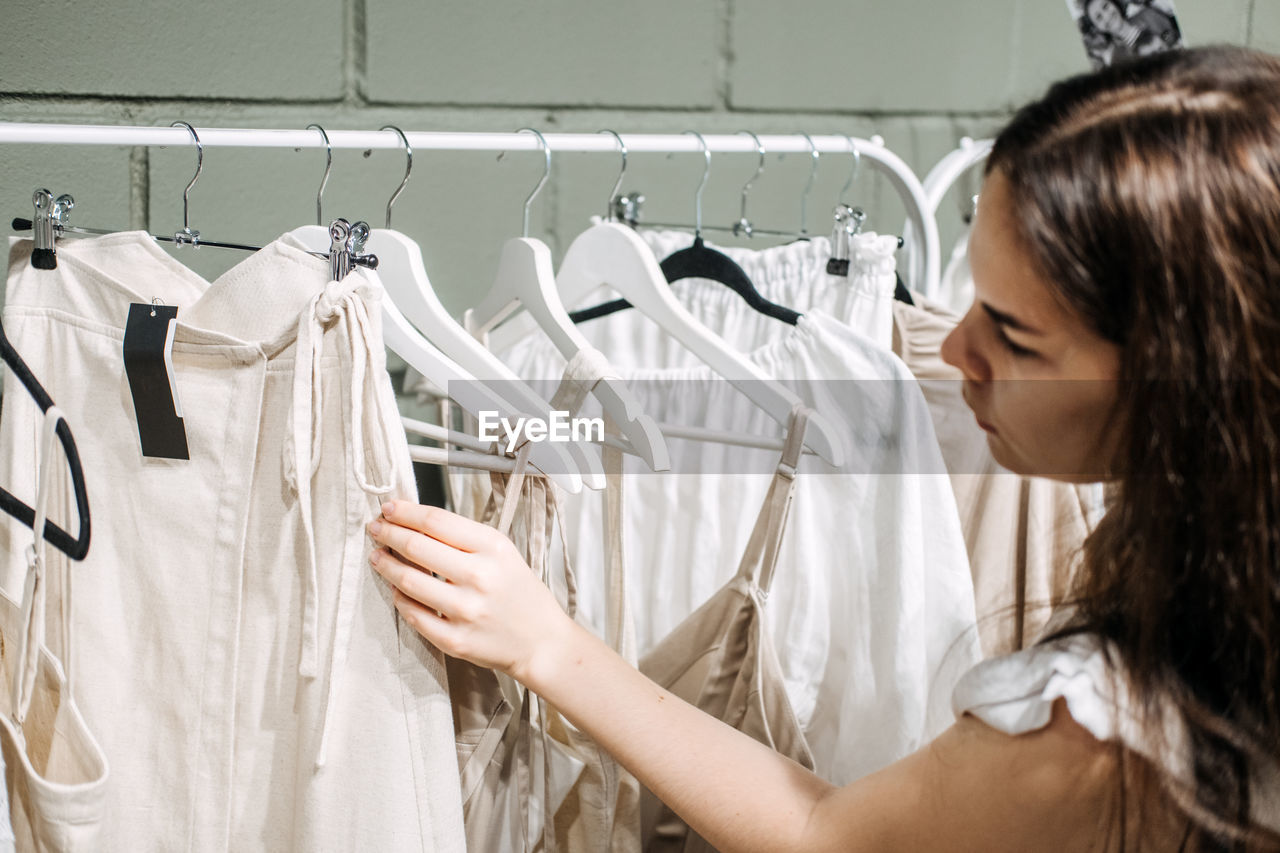 Sustainable fashion, slow fashion. close up shot of female hand taking clothing rack with natural