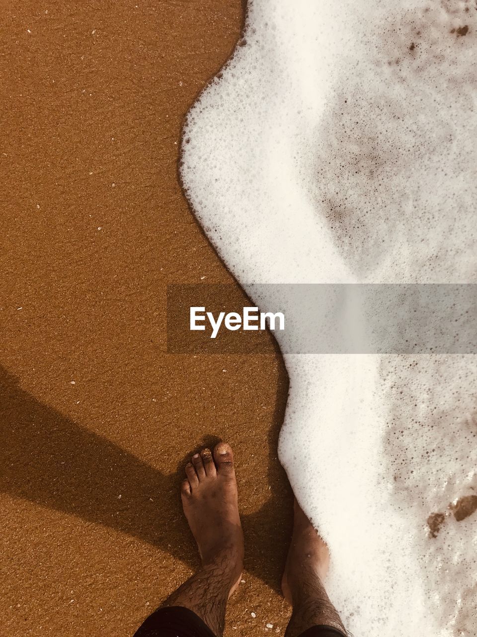 LOW SECTION OF WOMAN STANDING ON SHORE