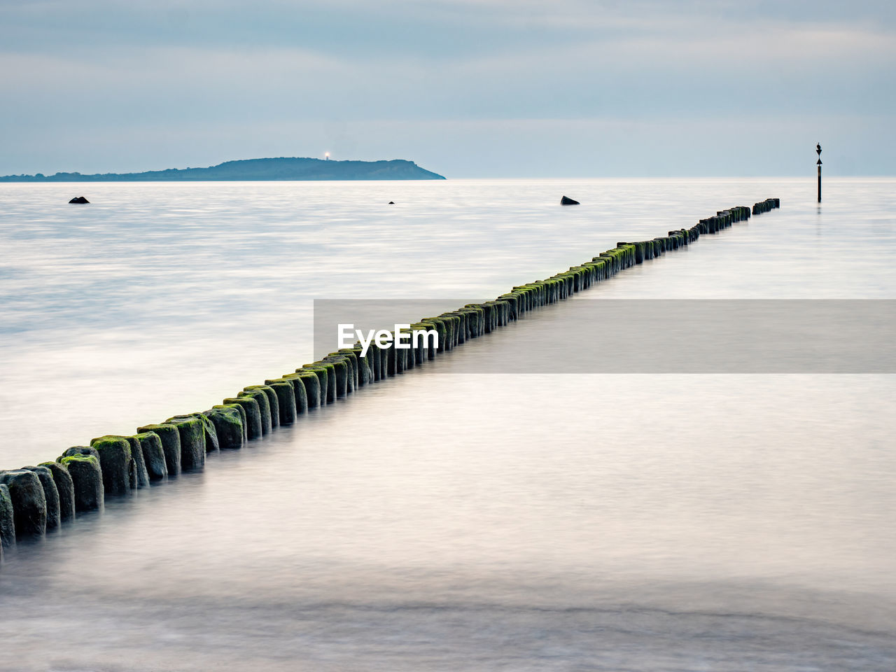 Hiddensee island with lighthouse and breakwater poles in smooth water of baltic sea ruegen island