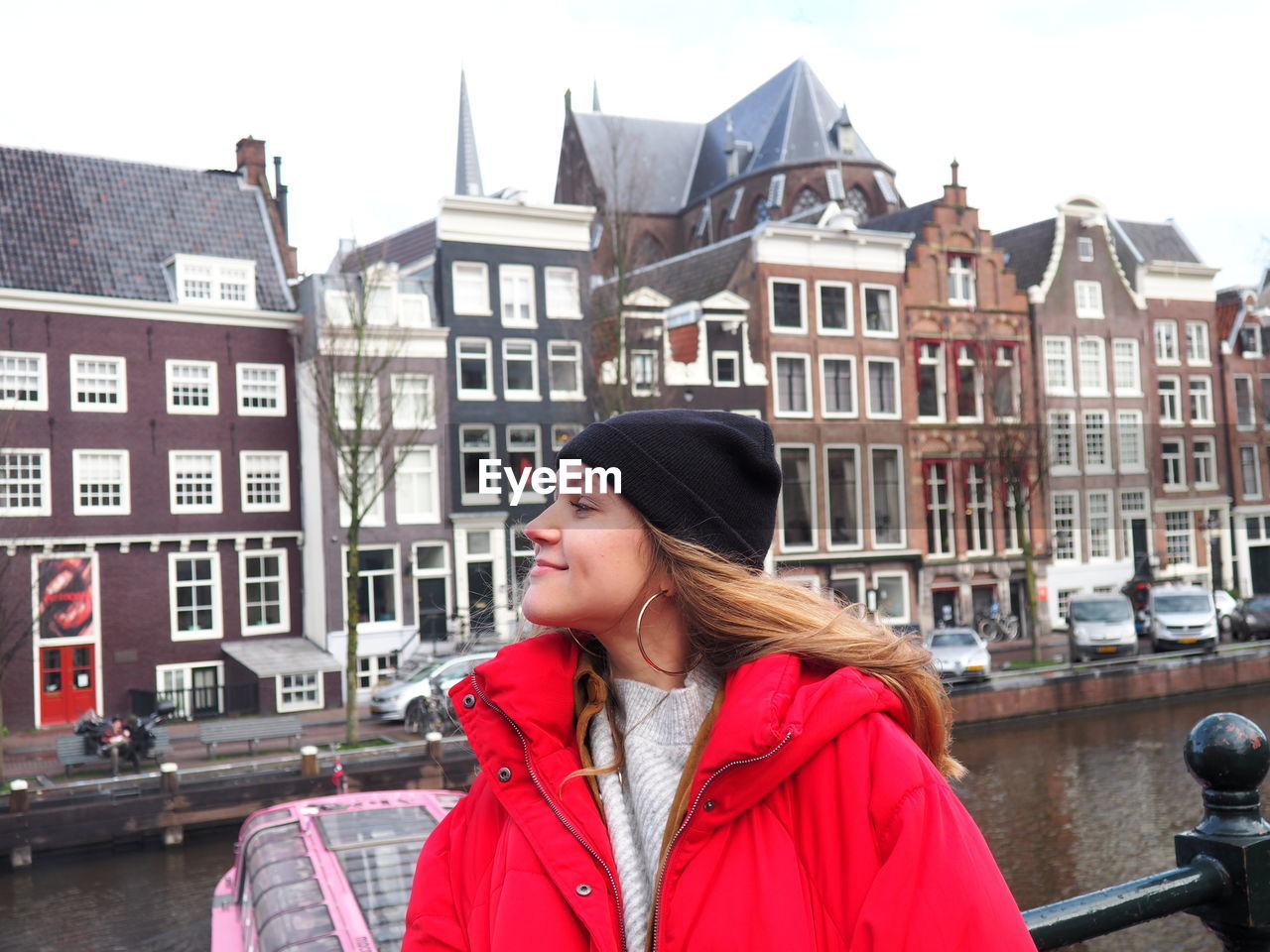 PORTRAIT OF WOMAN STANDING BY BUILDINGS IN CITY