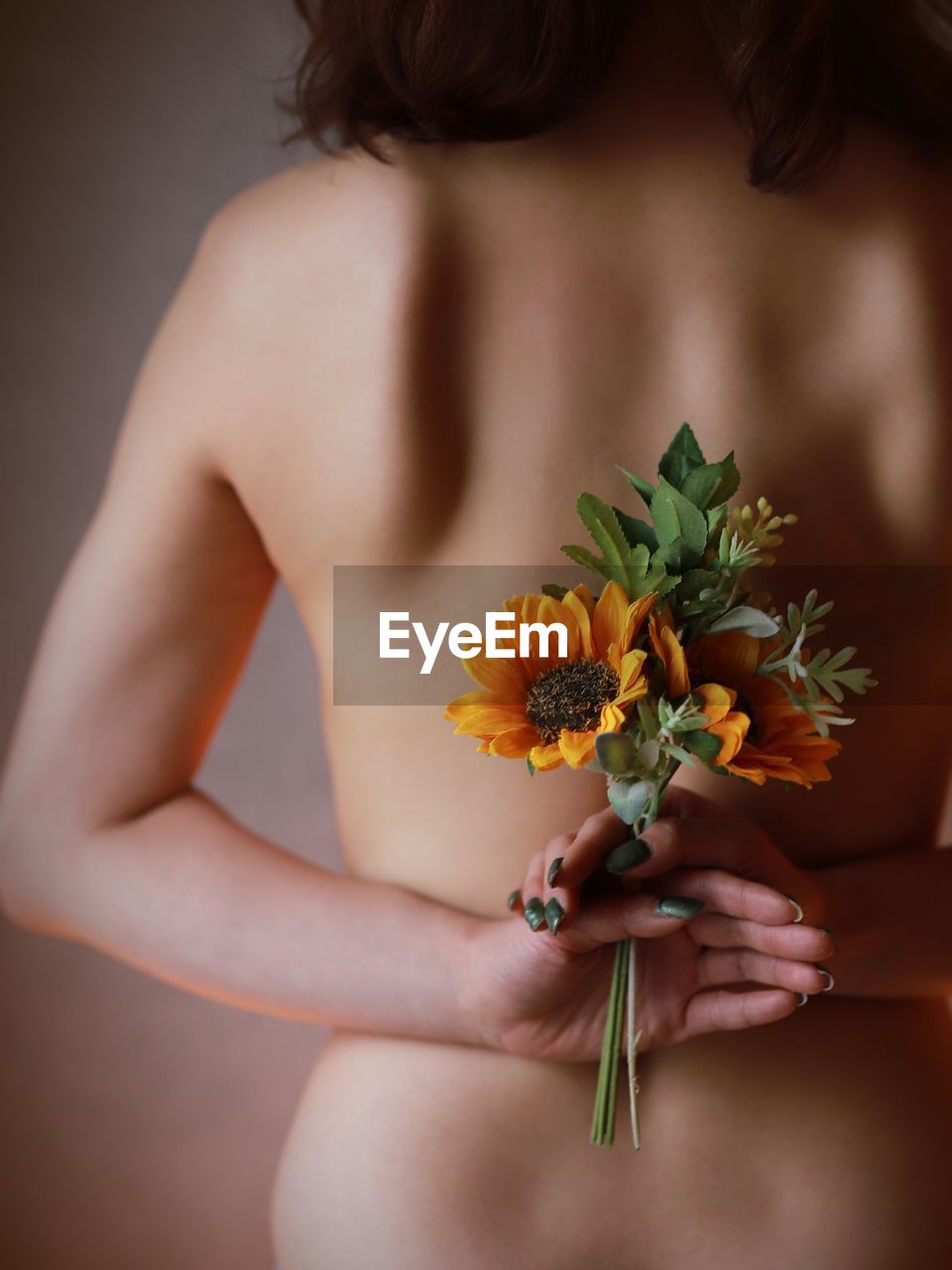 Naked woman holding flowering plant