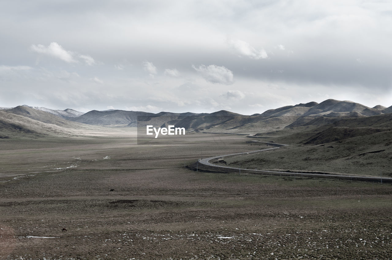 Scenic view of road by mountains against sky