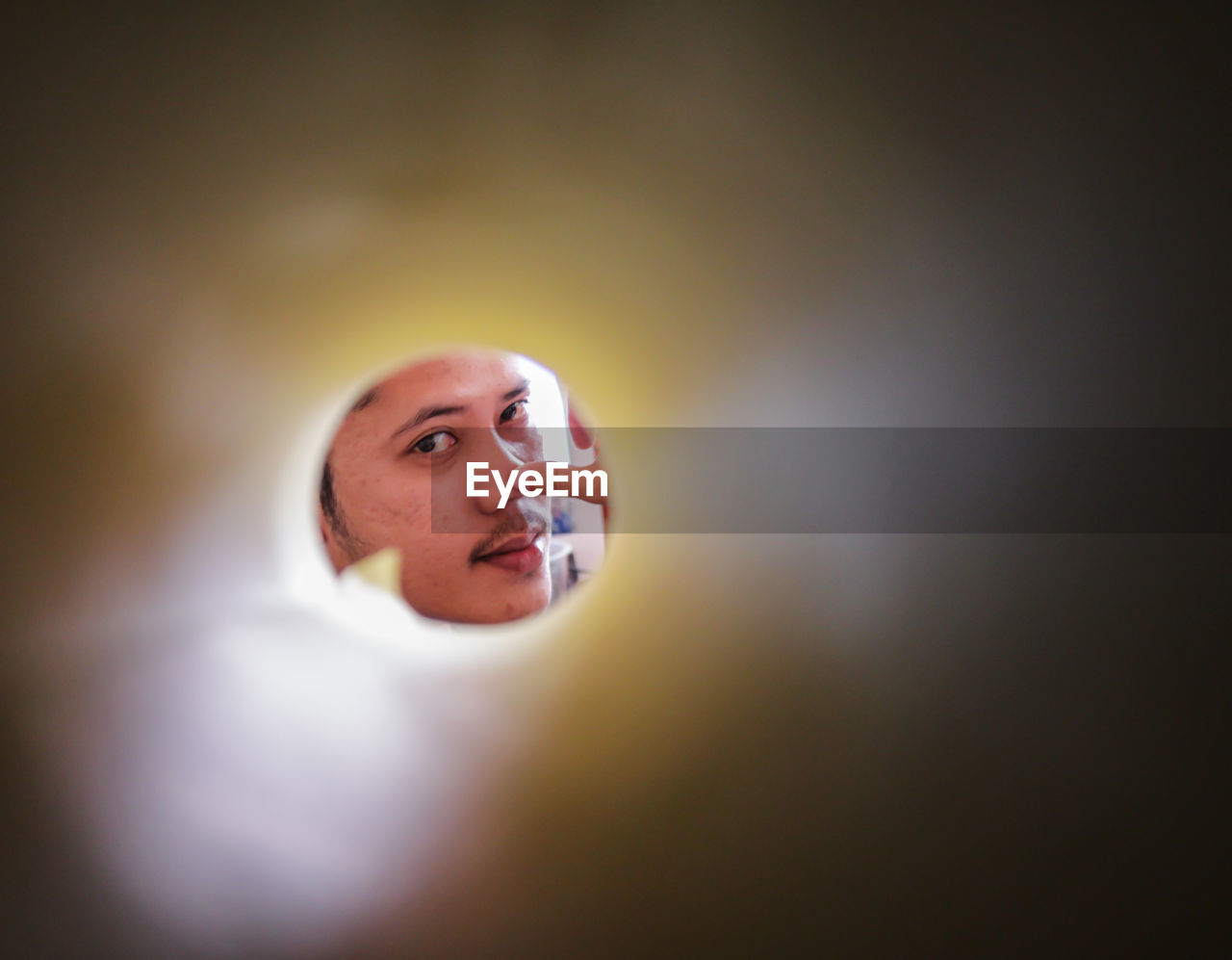 Portrait of man seen through rolled paper