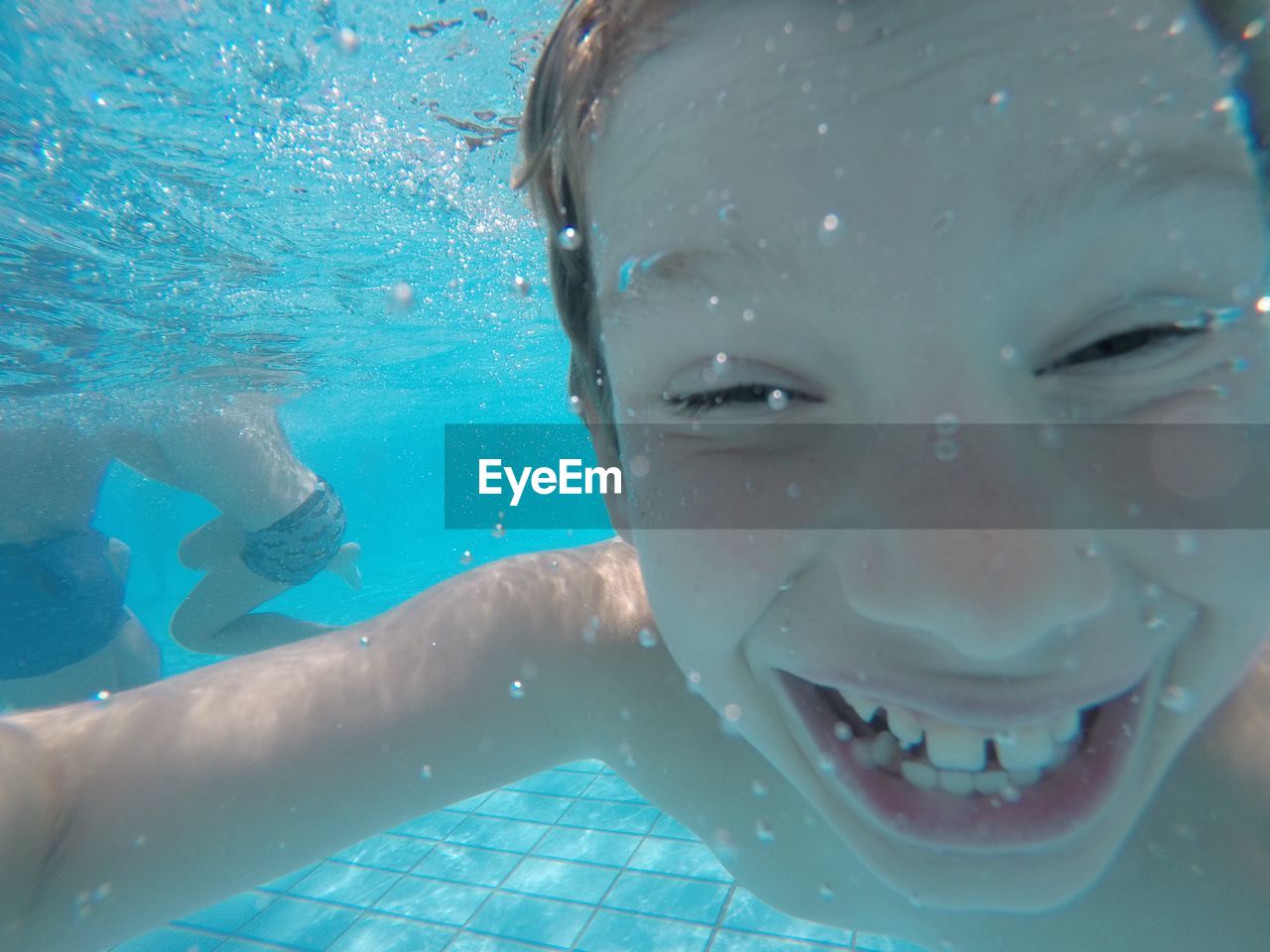 Close-up of cheerful boy swimming in pool