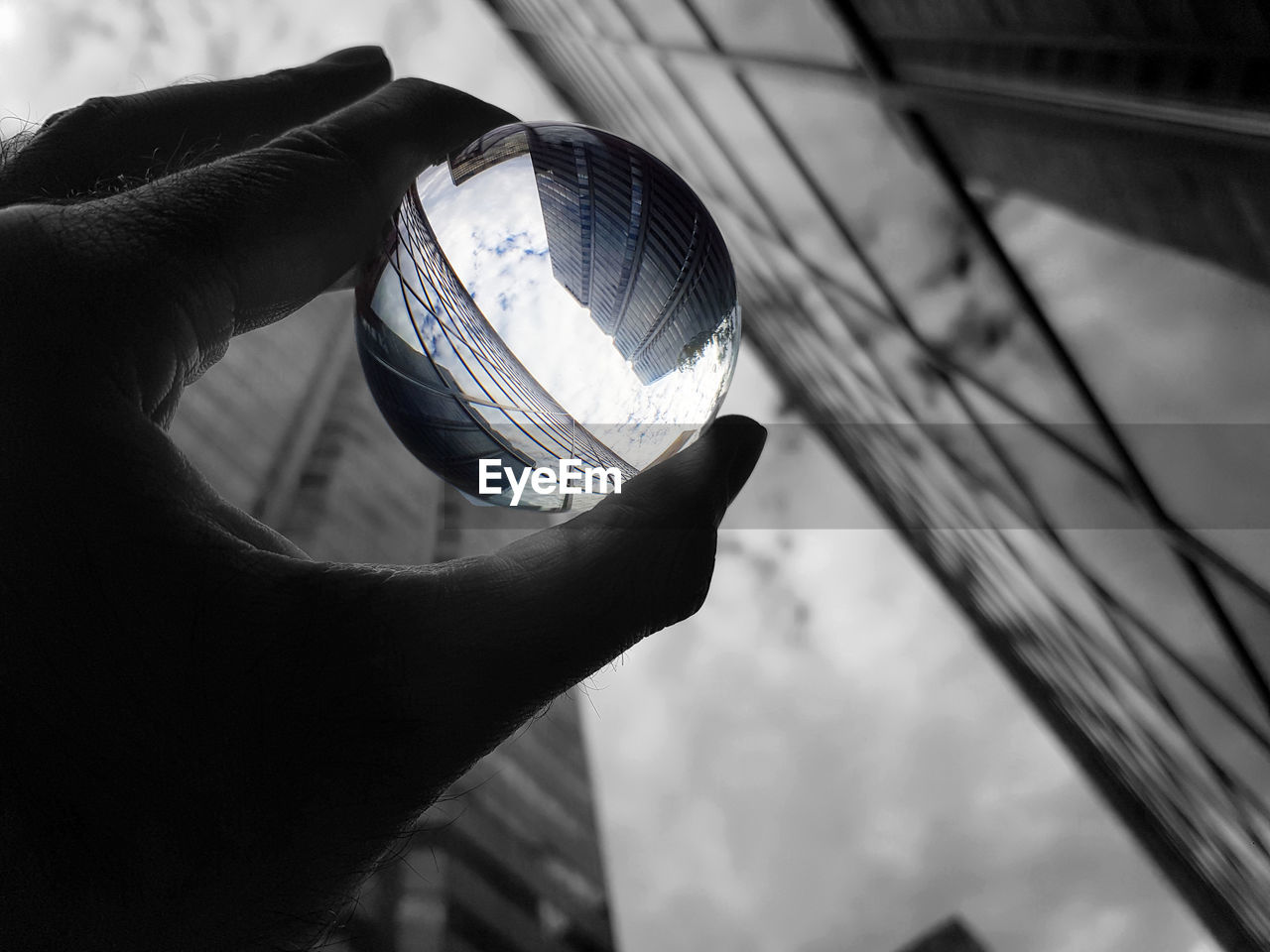 CLOSE-UP OF HAND HOLDING GLASS WITH REFLECTION OF PERSON