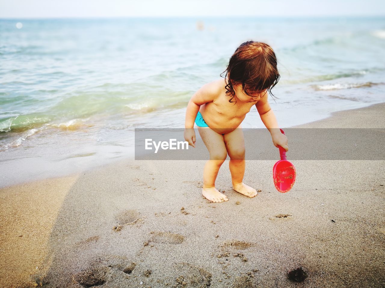 Full length of shirtless baby girl playing on shore at beach