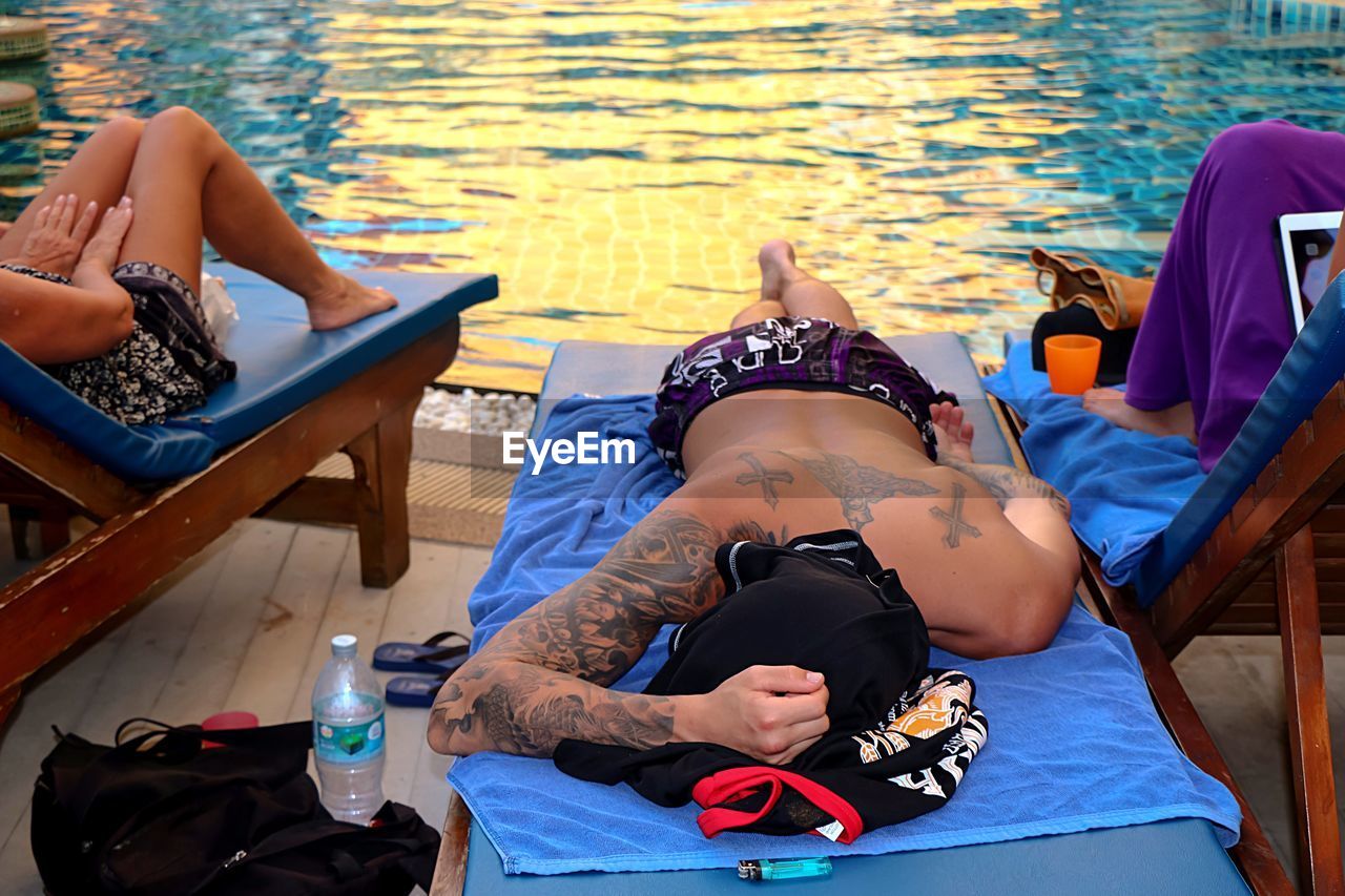 High angle view of man lying down on lounge chair by swimming pool