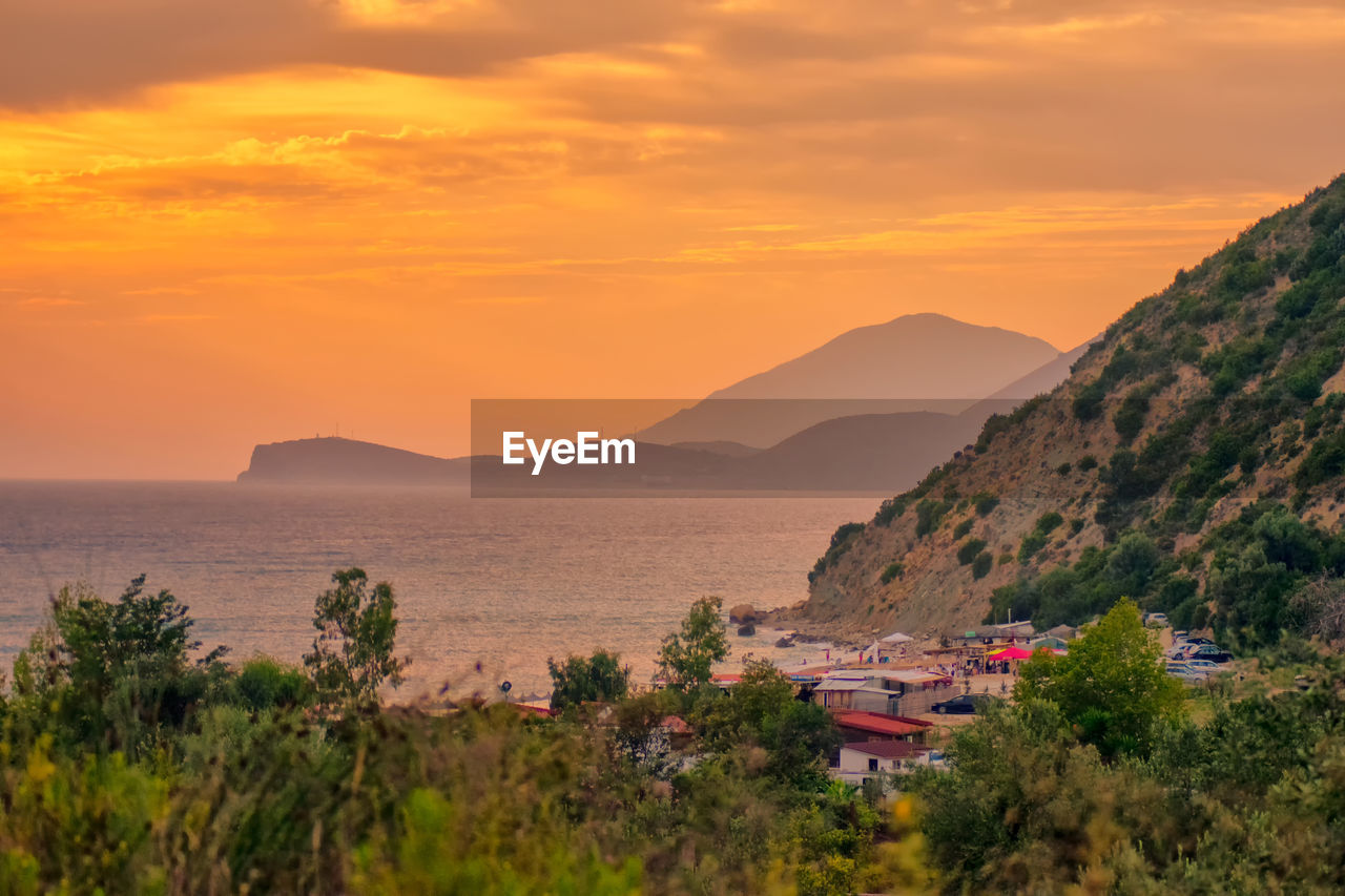 Scenic view of sea and mountains against orange sky