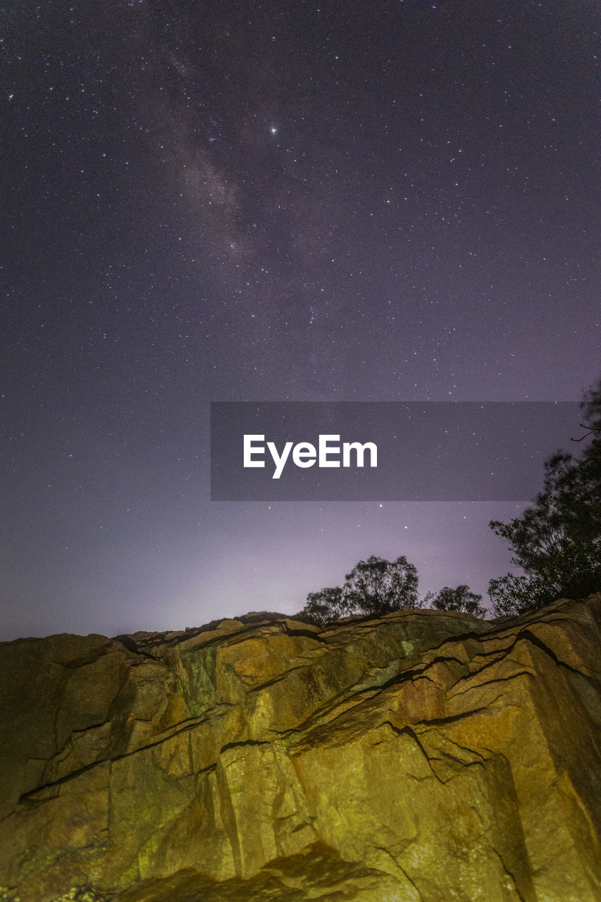 LOW ANGLE VIEW OF TREES ON MOUNTAIN AGAINST SKY AT NIGHT