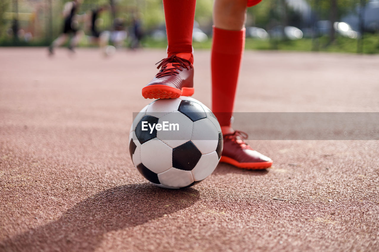 Unrecognizable girl holding soccer ball with one foot