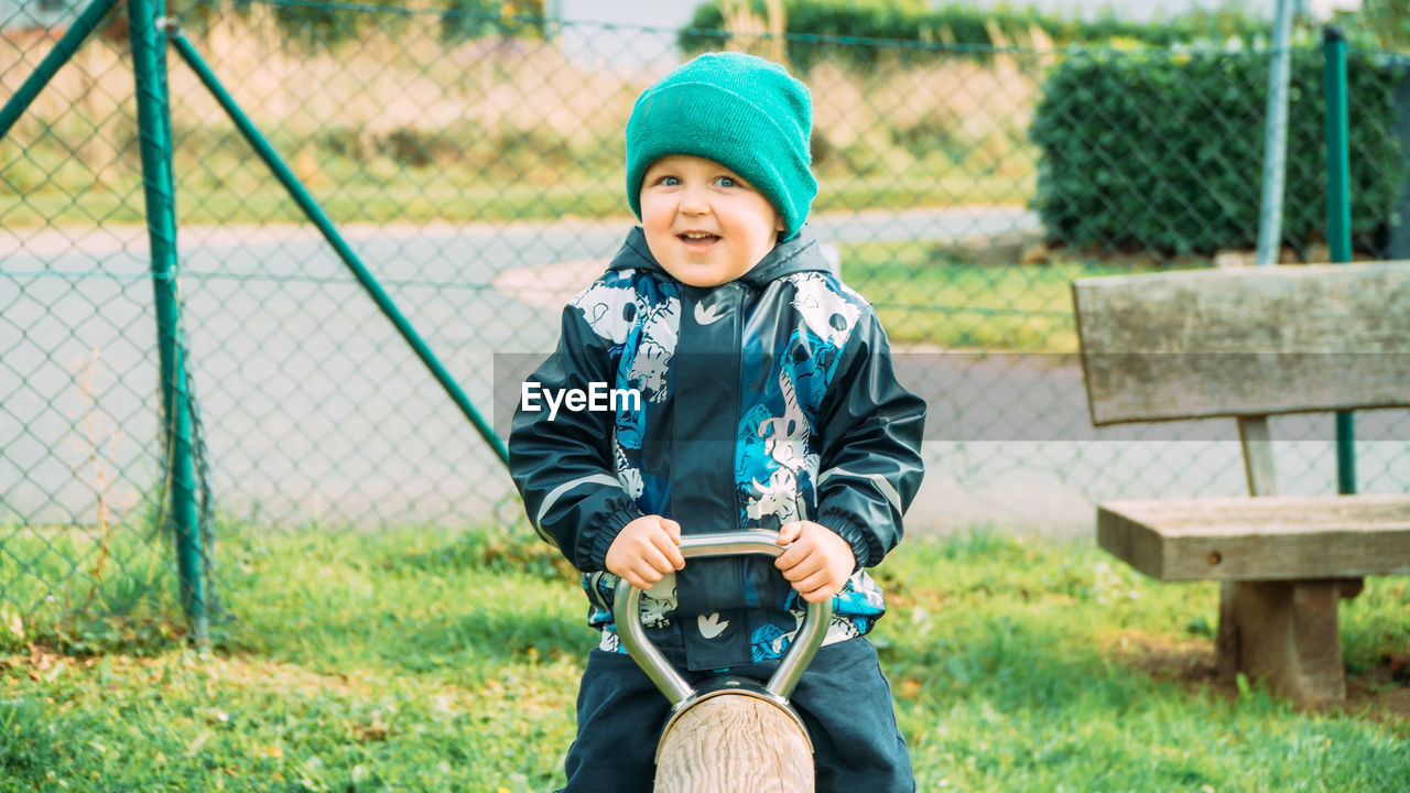 Little boy dressed in warm clothes playing on the playground on an autumn day