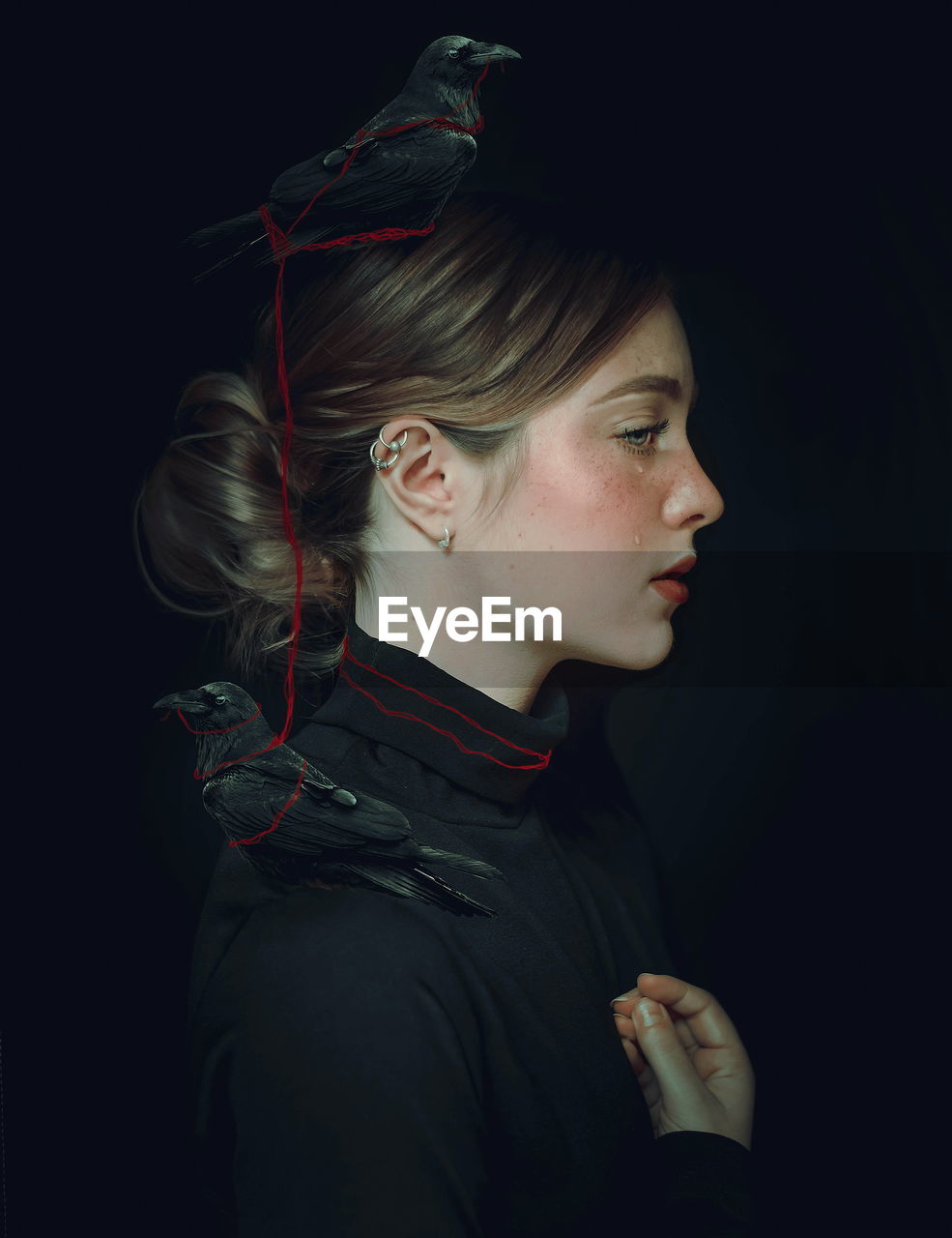 Side view of woman with bird against black background