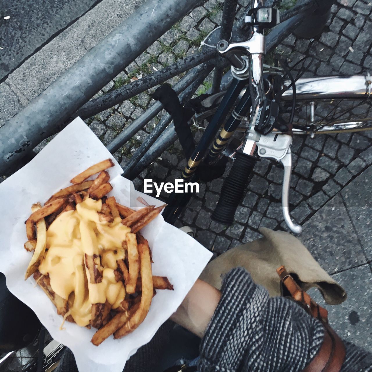 Midsection of woman holding french fries by bicycle on footpath